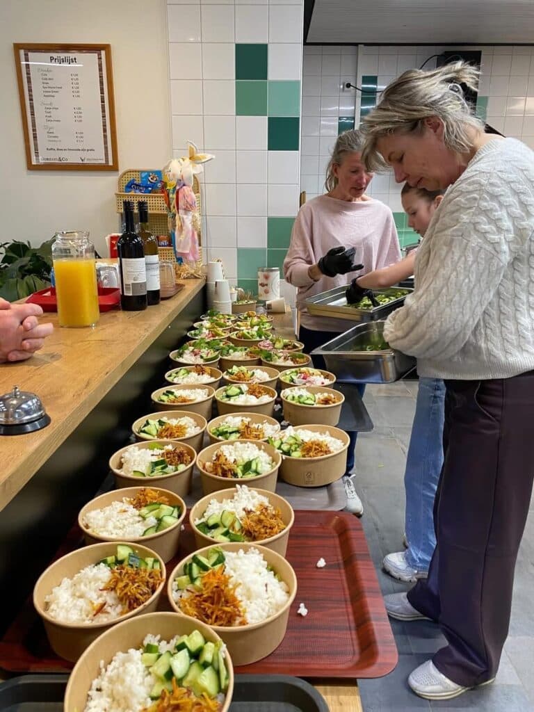 Keuken tijdens de Hawaiiaanse avond: rijen kommen met rijst, groente en toppings klaar voor bediening.
